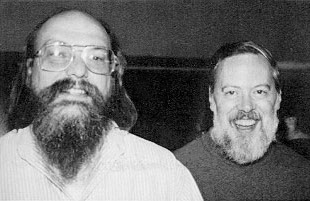 Ken Thompson and Dennis Ritchie, respectively standing side by side smiling into the camera